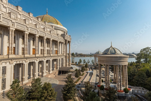Majestic view of the Navruz Palace in Dushanbe, Tajikistan, featuring grand columns, domed pavilions, and a scenic lakeside landscape under a clear blue sky