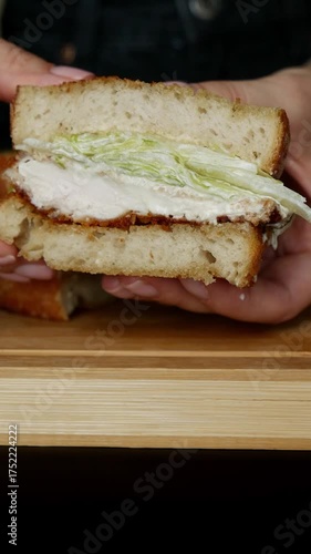 Female hands holding half of crispy chicken Caesar toast sandwich with visible filling