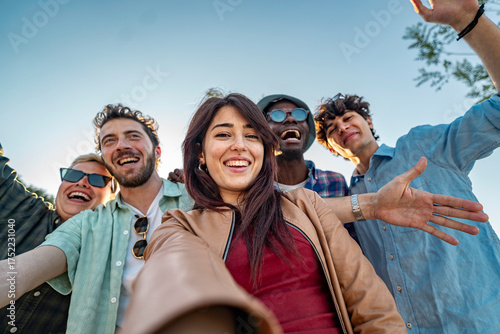 Group of happy multiethnic friends taking a selfie outdoors. Spontaneous moment of fun, travel and authentic lifestyle with a wide angle view.