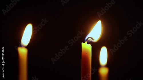 Burning candle flames glowing in the dark, symbolizing warmth, hope, and remembrance. Perfect for concepts of spirituality, meditation, or calm atmosphere