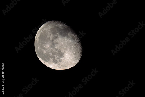 Nearly full moon displaying craters in the black night sky. 