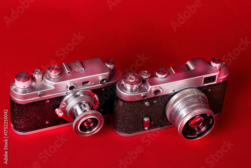Old film 35 mm compact cameras on red background, isolated.