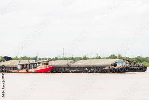 red river tugboat pushing covered cargo barge on inland waterway