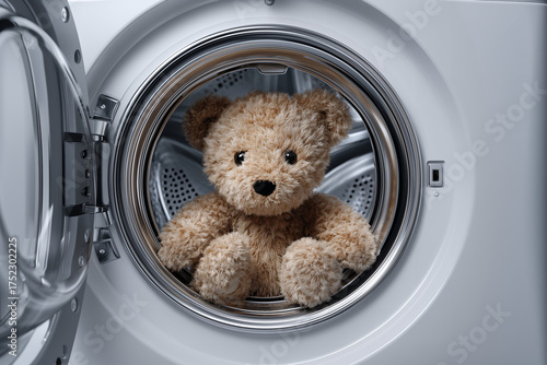 A cute plush teddy bear sitting inside the drum of a washing machine. Perfect for themes like family life, cleaning, parenting, or childhood memories.