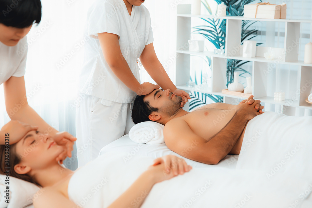 Obraz premium Caucasian couple enjoying relaxing anti-stress head massage and pampering facial beauty skin recreation leisure in dayspa modern light ambient at luxury resort or hotel spa salon. Quiescent