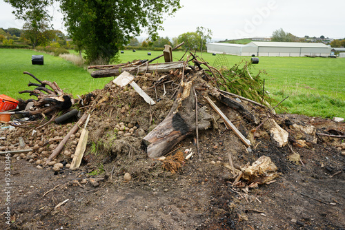 Large messy pile of garden waste, organic debris, wood, and discarded items on a farm field edge in Crich Derbyshire England.