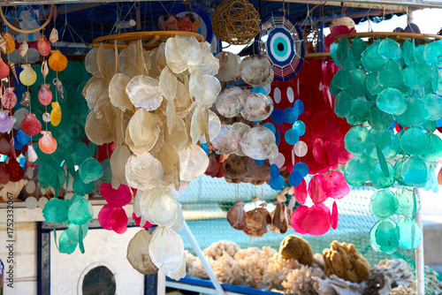 Fototapeta Naklejka Na Ścianę i Meble -  Colorful handmade shell and capiz decorations hanging at a seaside market stall, creating a vibrant display of natural and artistic crafts.