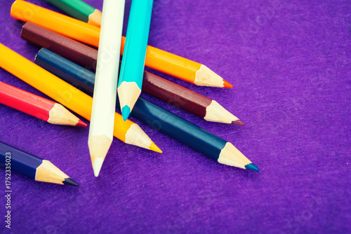 Nine multicolored pencils on a purple felt background. Different colored pencils with space for text. Back to school. Art lessons.