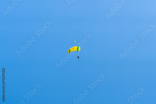 Skydivers gliding in blue sky in distance
