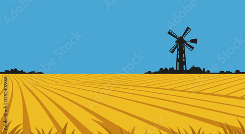 Silhouette windmill against blue sky with golden field in foreground