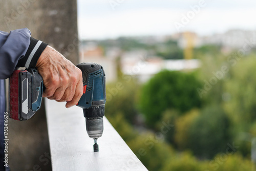 Close up worker's hand using cordless drill for outdoor construction task