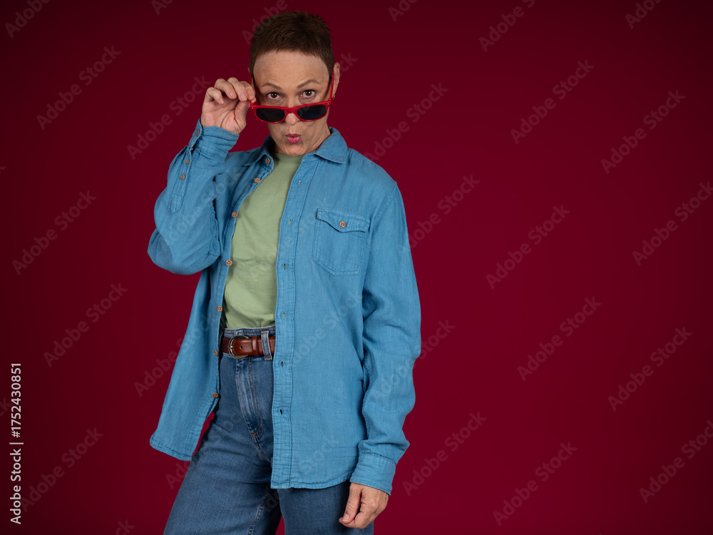 Fototapeta premium Person holding red sunglasses looking curiously over glasses