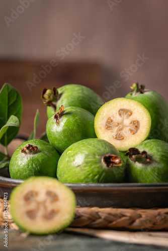 Wallpaper Mural A close-up, moody still life of a metal bowl filled with green feijoa, with one fruit sliced in half, on a rustic wooden table Torontodigital.ca