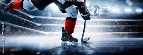 Hockey player on the rink at high speed. Close-up of hockey skates, stick, and puck on a skating rink. Focus on the puck. Hockey player in action
