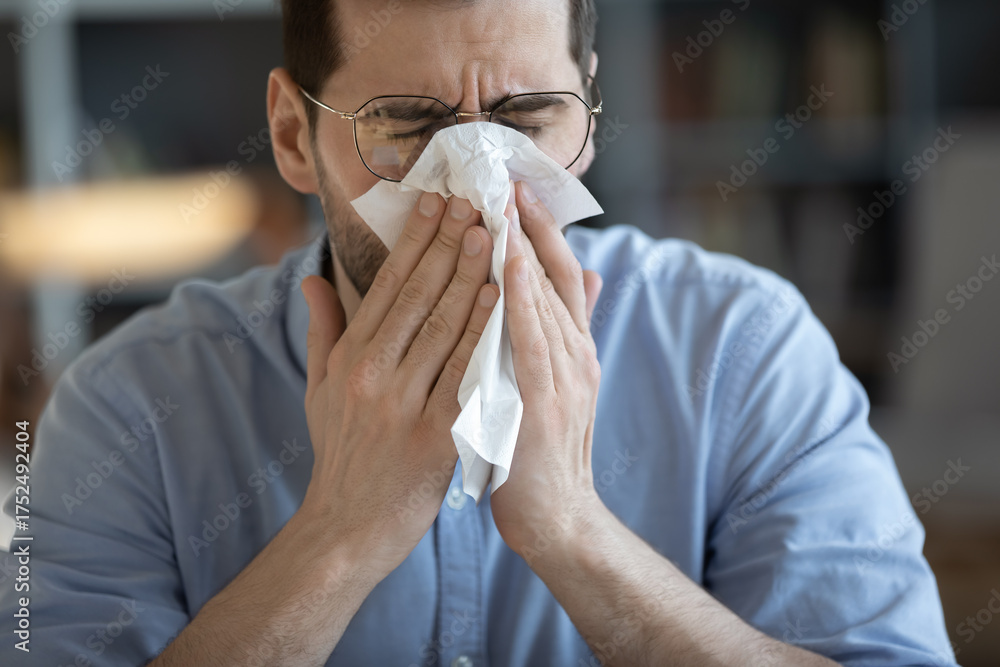 © fizkes - Closeup portrait sick man covering nose mouth with paper napkin