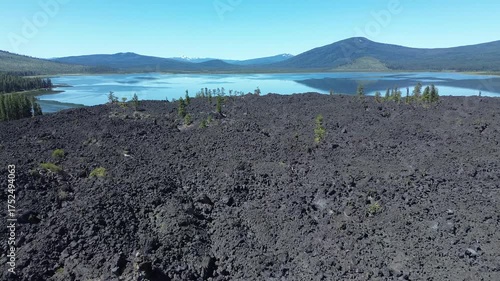Lava flow in central Oregon. High angle flyover shows the large extent of the ancient flow with a lake and mountains in the background.