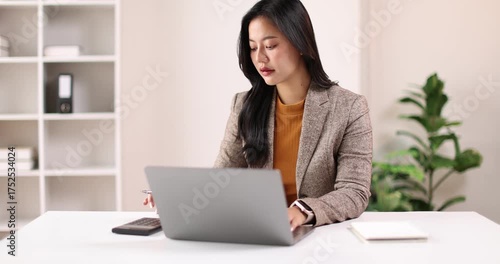 Adult woman working at her desk in a bright office, business casual jacket digital nomad remote work concept
