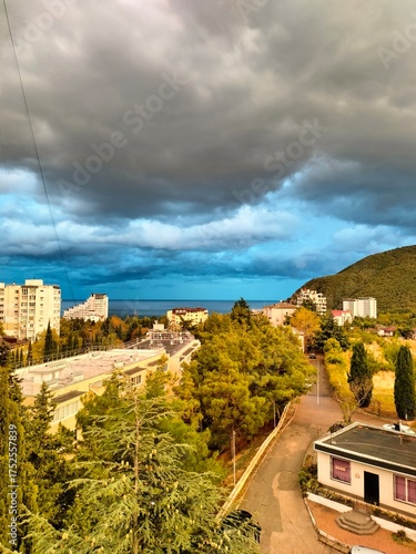 Wallpaper Mural rustic landscape. the sea, the buildings, the trees. large clouds in the sky. bright natural colors Torontodigital.ca