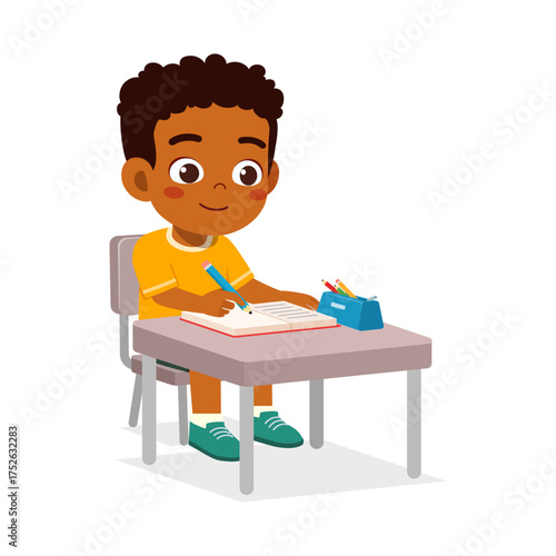African American schoolboy studies at desk writing in notebook concentrated expression