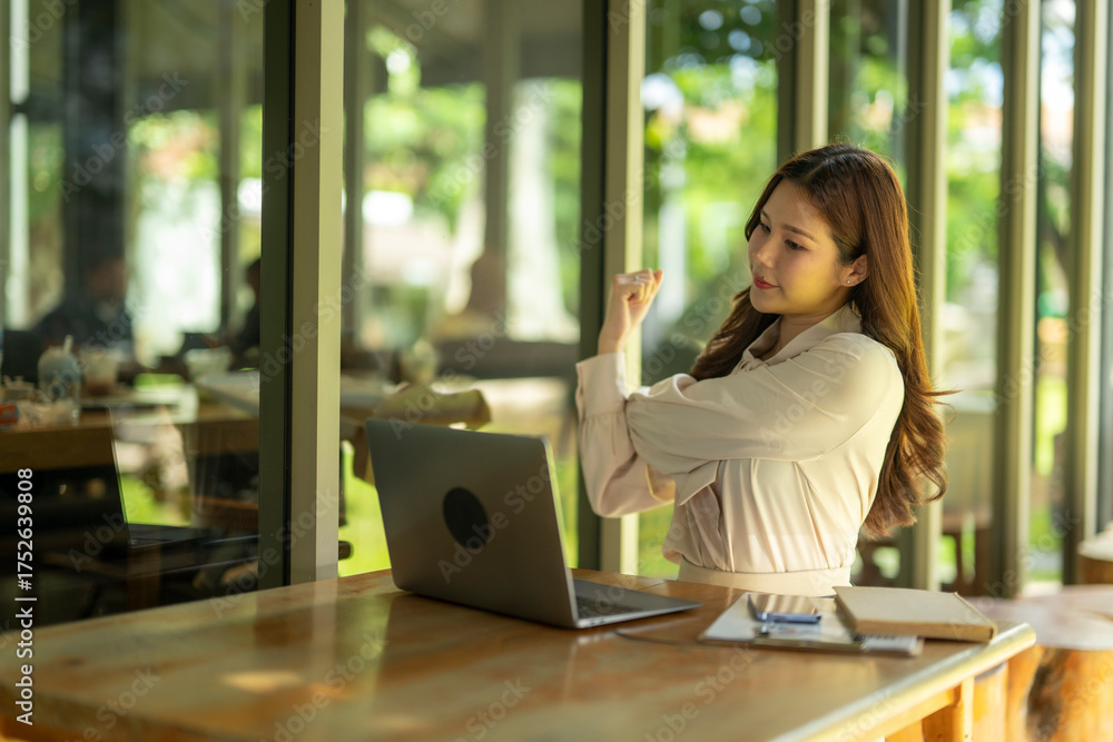Fototapeta premium Young woman stretching arm taking break from laptop