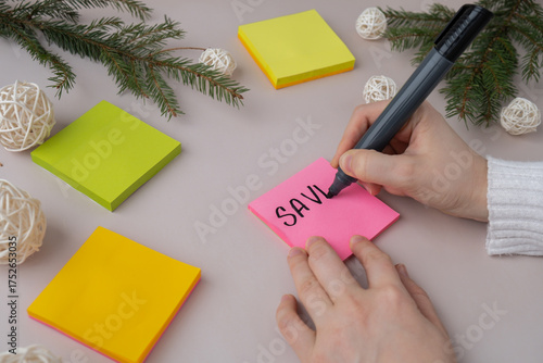 Female hands writing handwritten new year resolutions aims goals on sticky notes. Preparation for New Year. Concept of planning and setting goals for personal development 