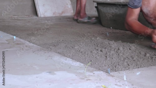Workers are using plastic buckets to scoop cement into containers for transport.