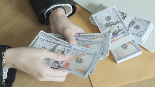 Businessperson counting stacks of dollars beside laptop, concept of profit, banking, and smart financial investment.