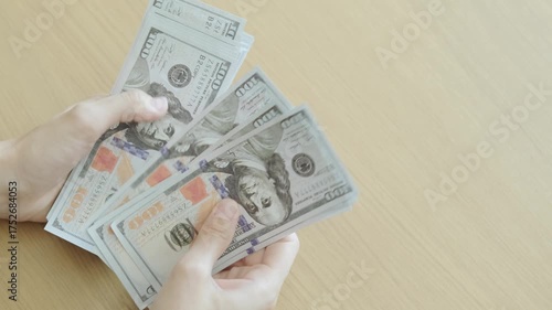 Close-up of hands counting dollar bills, representing cash flow, financial planning, and investment management for business growth.