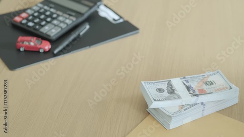 Car dealer handing over car key to buyer with dollar bills on table, concept of car purchase, loan approval, and successful financial transaction.