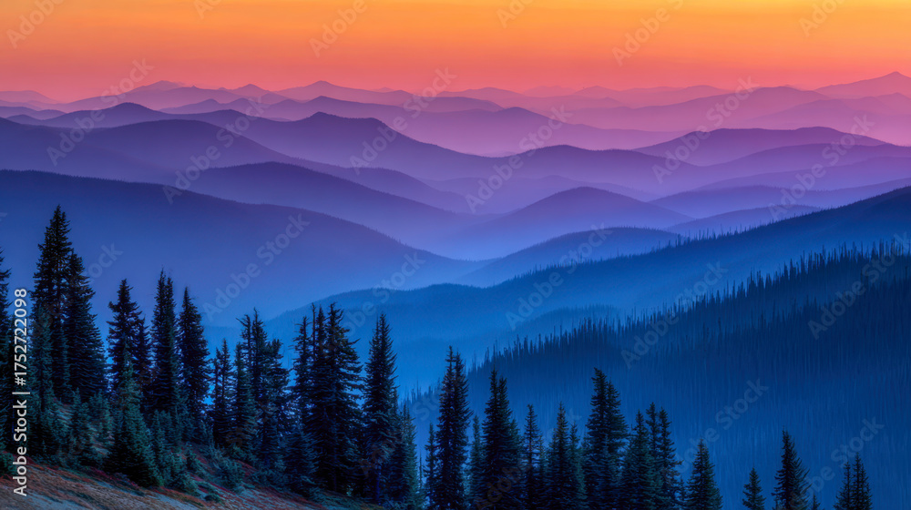 Obraz premium Layers of misty mountain ridges fading into a colorful sunset sky with silhouetted pine trees in the foreground creating a peaceful natural landscape scene