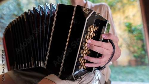 Photos Musician fingers play traditional bandoneon at home backyard.