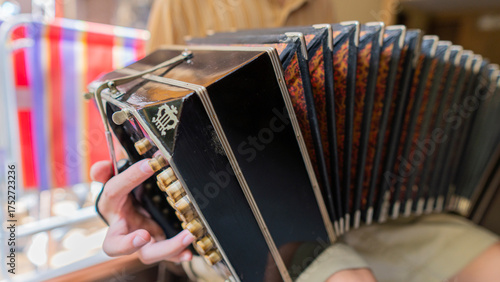 Musician's fingers plays tango on bandoneon in lively space setting