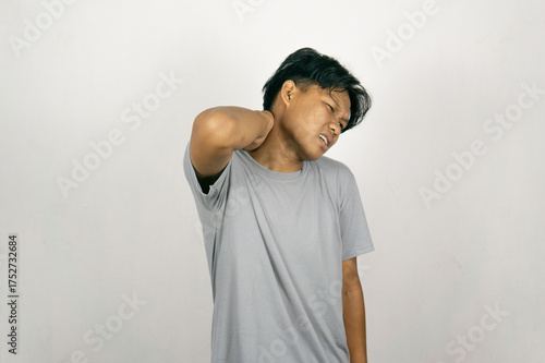 Vászonkép Young Asian man experiencing work related muscle pain and stiffness