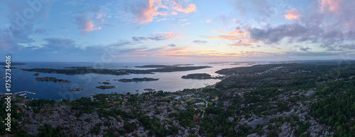 Panoramic Aerial View of Rocky Coastline and Islands Near Strömstad, Sweden at Dusk with Dramatic Clouds and Vibrant Sunset Colors Over the Calm Sea