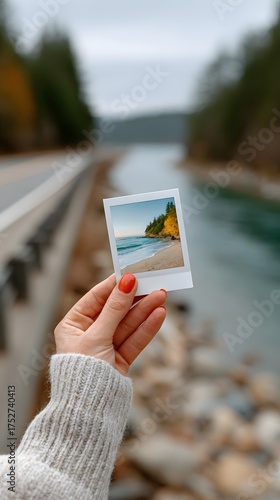 Hand holding Polaroid photo of sunny beach, travel memories, autumn road trip concept