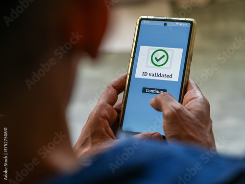 Man got successful ID validation message on his mobile phone confirming his identity document is authentic. Selective focus on the display.