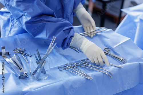 Scrub nurse arranging sterile surgical instruments on operating room table