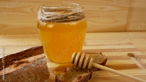 Wallpaper Mural Fresh golden honey in a glass jar with a wooden spoon spreading it on a piece of buckwheat baguette. Healthy natural dessert concept Torontodigital.ca