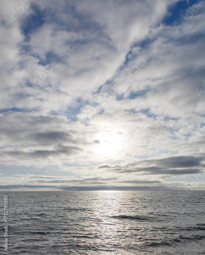 A calm ocean with a bright sun shining on the water