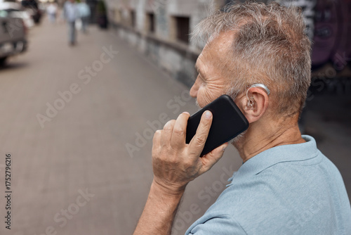 Using your hearing aids with a smartphone . Senior man with hearing aid behind the ear has a full life and can hear interlocutor in phone