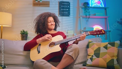 Latina beautiful woman playing guitar in living room at home. 