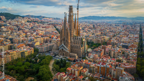 Aerial view of the Sagrada Familia's spires piercing the sky, a symphony of stone amidst the urban tapestry, Barcelona, Catalunya, Spain.