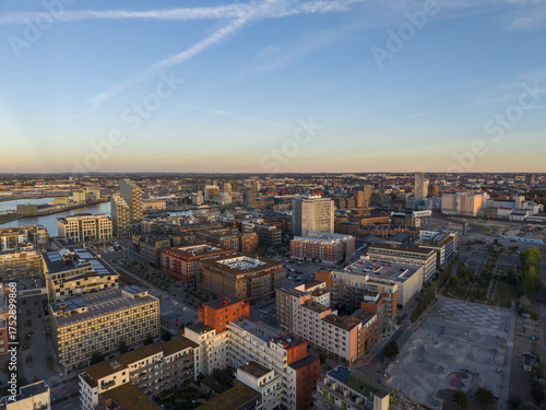 Wallpaper Mural Aerial view of buildings casting long shadows under a warm sunset glow, with the harbor reflecting the sky's golden hues in Nyhamnen, Malmo, Sweden. Torontodigital.ca