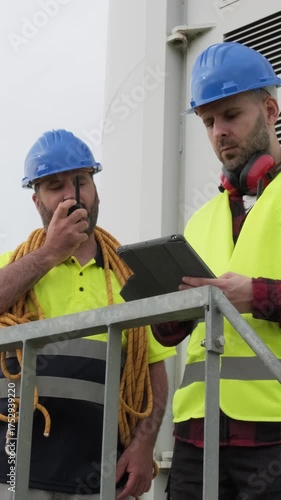 Wind turbine technicians coordinating maintenance on a tablet