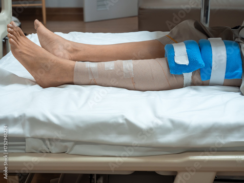 Photography Patient lying in hospital bed with bandaged knee and cold pack after ACL and meniscus surgery