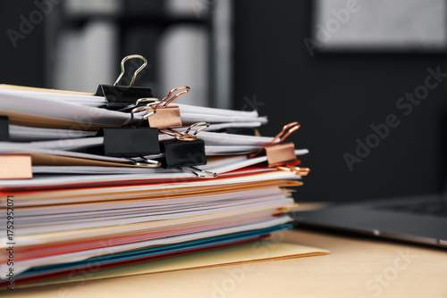 Foto Many folders with documents and laptop on wooden desk, closeup