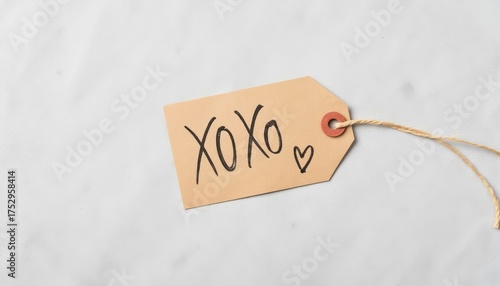 Gift tag with handwritten 'XOXO' and heart symbol on marble background  