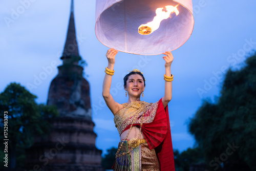 Asian women wearing thai dress releasing sky lantern into the night sky in yi peng festival, Traditional dress costume, Floating lanterns ceremony traditional Lanna Buddhist ceremony.