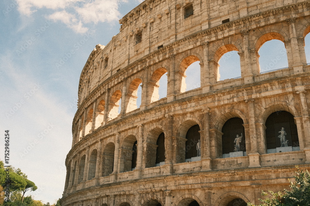 Obraz premium Historic view of the Colosseum in Rome, iconic ancient Roman amphitheater and UNESCO World Heritage site. Symbol of Roman Empire and popular travel destination.