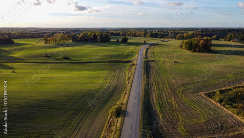 Aerial View of a Country Road Through Green Fields in the Autumn Golden Hour